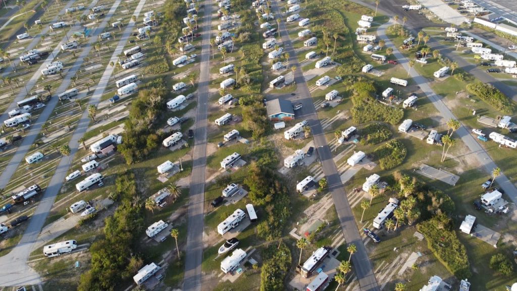Aerial shot of a lush campsite filled with RVs and trailers during the day.
